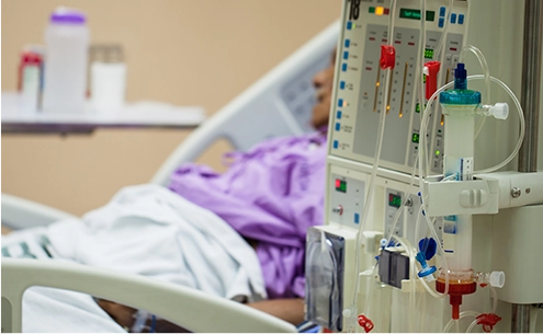Patient in hospital bed with IV drip run by valve