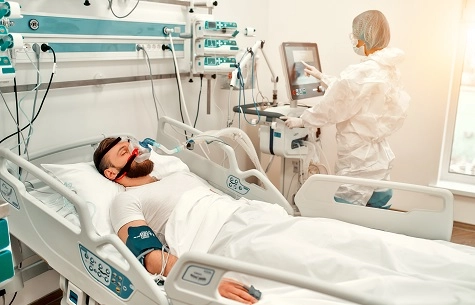 Man in hospital bed with respirator on his face